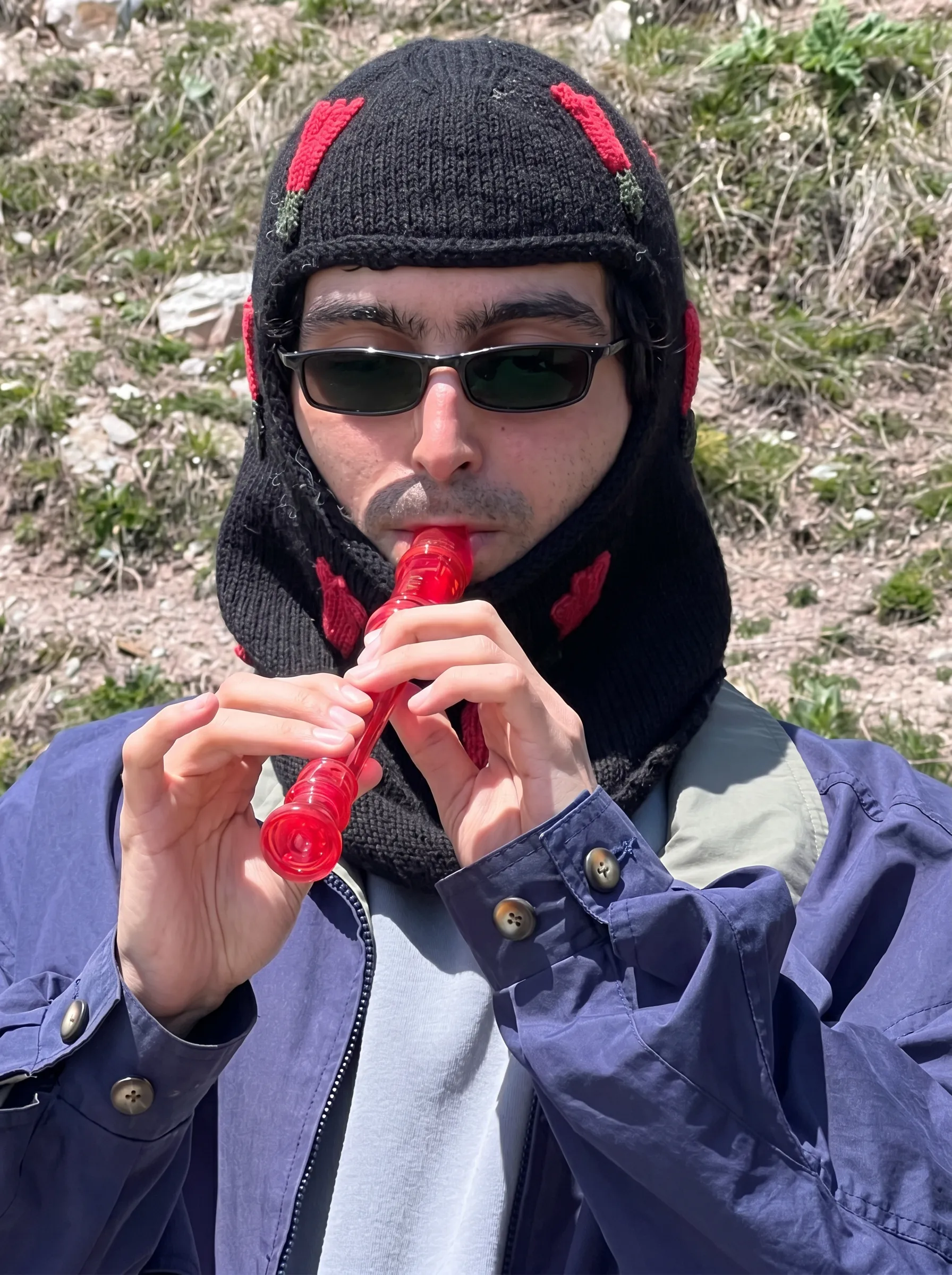 Raf Tadevossian playing a red recorder in a black knitted hat